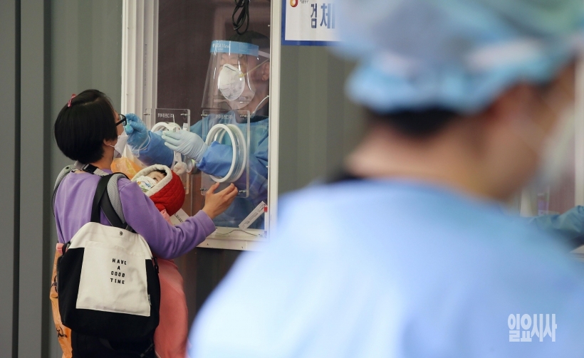 ▲ 지난달 29일, 서울 중구 서울역광장에 마련된 임시선별진료소에 한 시민이 아기를 안고 코로나 검사를 받고 있다. ⓒ박성원 기자